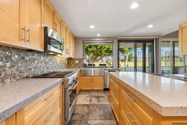 a large kitchen with stainless steel appliances granite countertop a lot of counter space and a sink