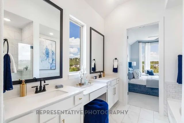 a spacious bathroom with a double vanity sink a mirror a bathtub and next to a window