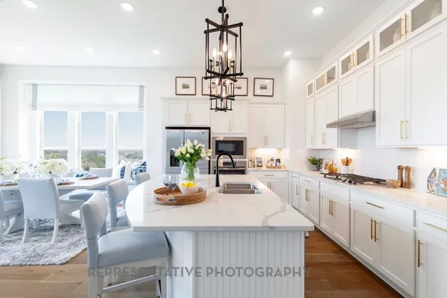 a kitchen with stainless steel appliances a dining table chairs stove and white cabinets