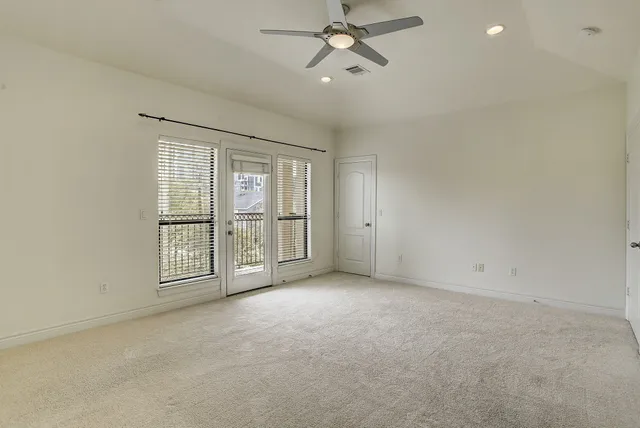 an empty room with chandelier fan and windows
