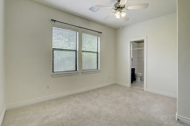 an empty room with chandelier fan and windows