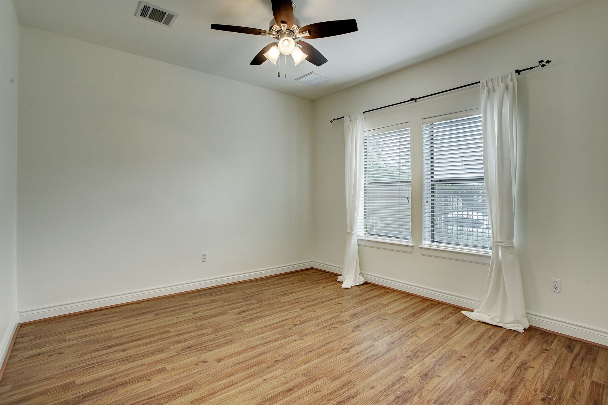 1403 Rosedale Street Houston, TX 77004 - Photo 4 of 18 an empty room with wooden floor chandelier fan and windows