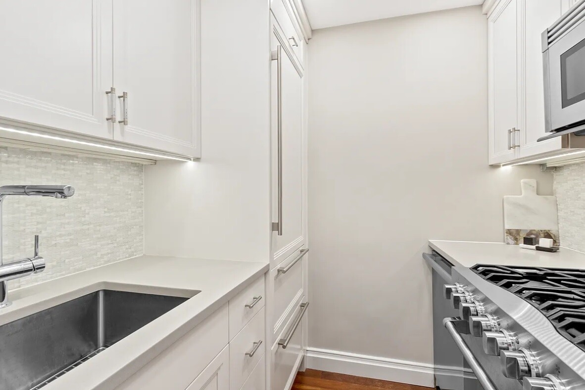 240 East 76th Street, Unit 6V Manhattan, NY 10021 - Photo 4 of 7 a kitchen with white cabinets and a stove