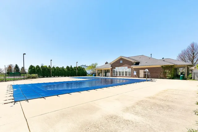 a view of swimming pool with lawn chairs and large tree