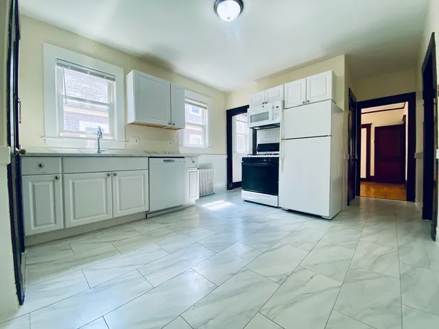 a kitchen with a refrigerator and white cabinets