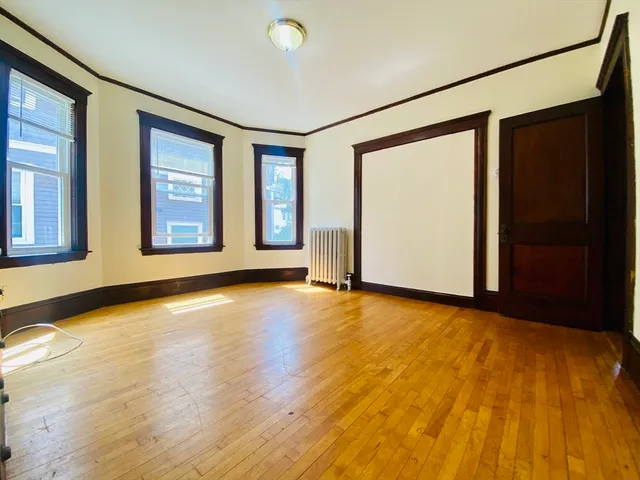 a view of an empty room with glass door and wooden floor
