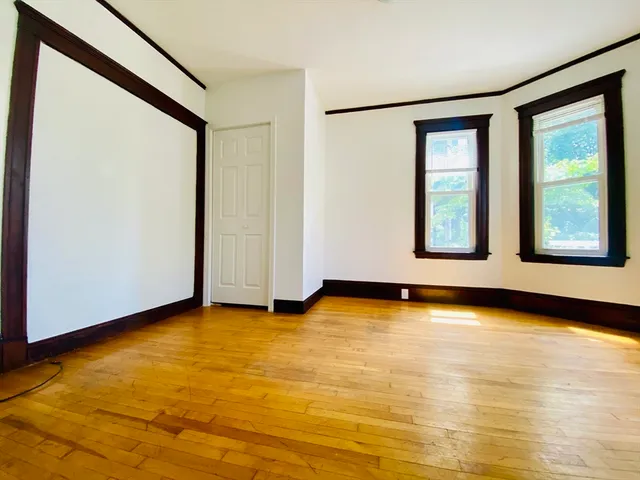 a view of an empty room with window and wooden floor