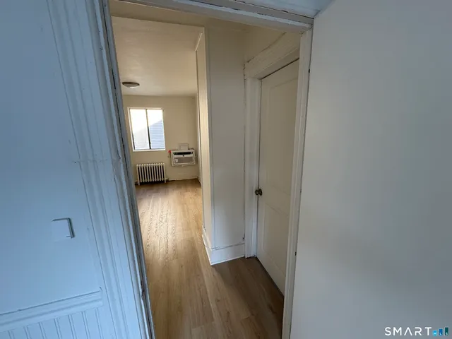 a view of a hallway with wooden floor and a bedroom