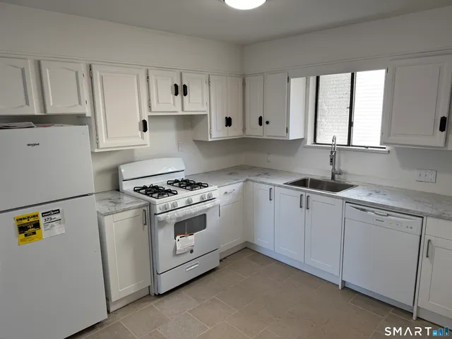a kitchen with granite countertop white cabinets and white appliances
