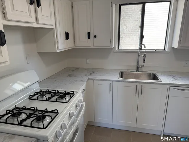 a kitchen with sink a stove and white cabinets