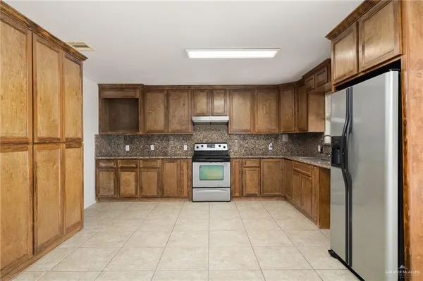 a kitchen with stainless steel appliances granite countertop a refrigerator and a stove top oven