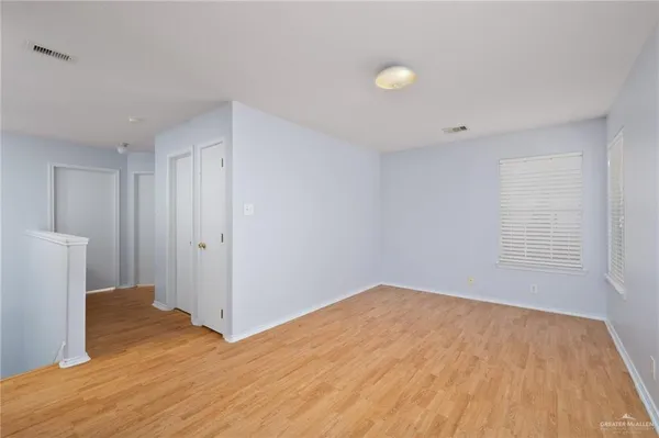 a view of empty room with wooden floor and fan