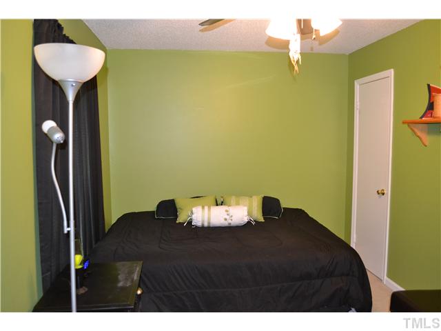 7712 Prospector Place Raleigh, NC 27615 - Photo 14 of 16 a bedroom with a bed and a chandelier
