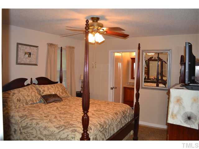 7712 Prospector Place Raleigh, NC 27615 - Photo 10 of 16 a bedroom with a large bed and a chandelier