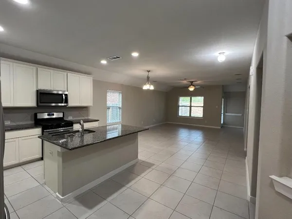 a kitchen with granite countertop a stove a sink and a microwave