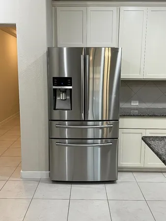 a metallic refrigerator freezer sitting inside of a kitchen