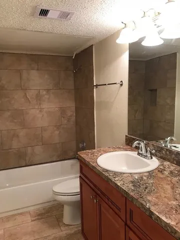 a bathroom with a granite countertop sink toilet and shower