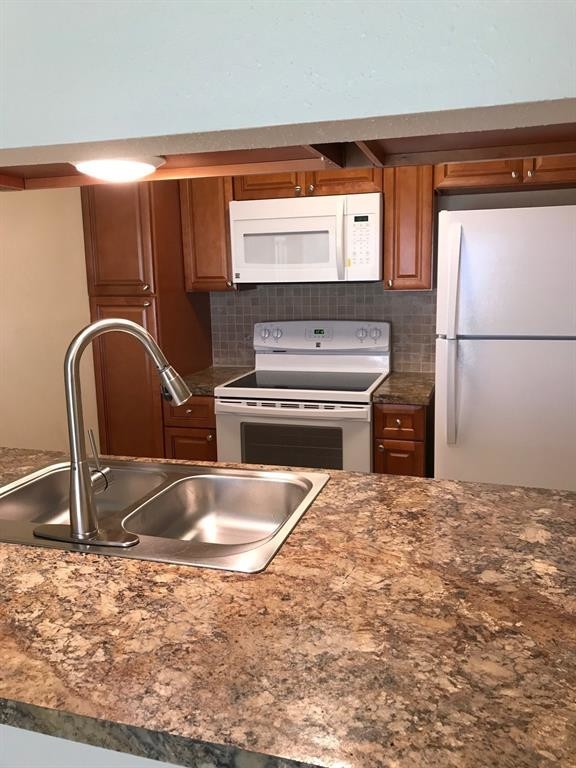 1947 Greenbriar Colony Drive, Unit 15518E Houston, TX 77032 - Photo 9 of 12 a kitchen with granite countertop a sink and a refrigerator