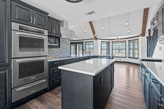 a kitchen with stainless steel appliances kitchen island granite countertop a stove a sink and a microwave