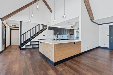 a view of an empty room with wooden floor and windows