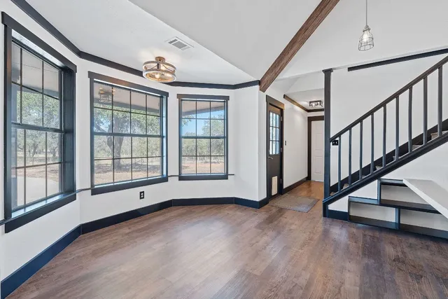 a view of an empty room with wooden floor and windows