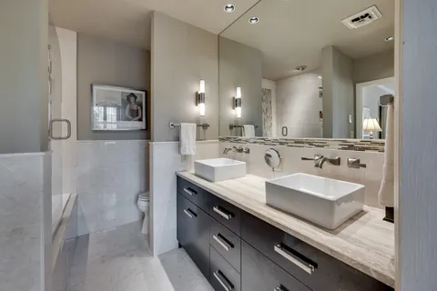 a bathroom with a double vanity sink a toilet and a tub