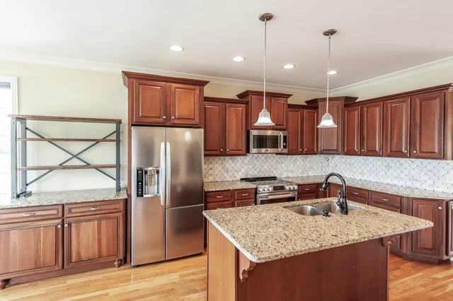 a kitchen with stainless steel appliances granite countertop a sink refrigerator and cabinets