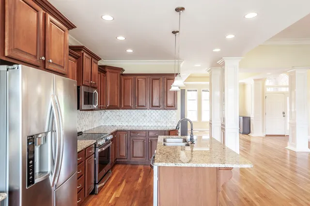 a kitchen with stainless steel appliances granite countertop a refrigerator a sink and a stove