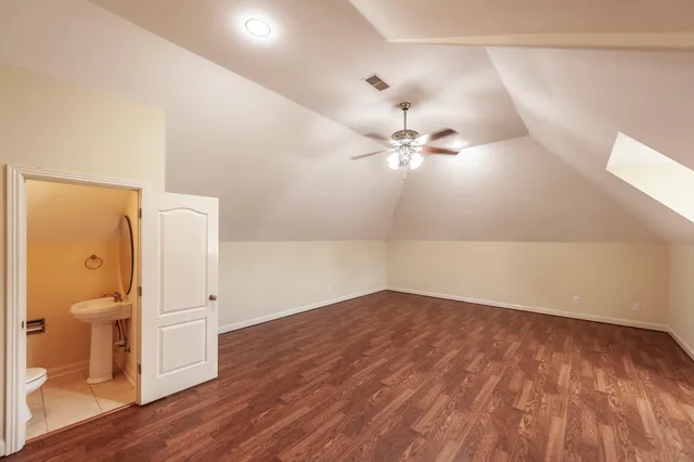an empty room with wooden floor and bathroom view
