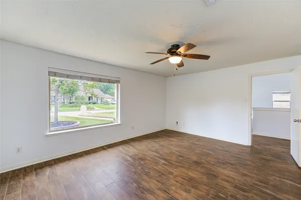 a view of an empty room with wooden floor and a window