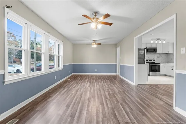 a view of empty room with wooden floor and window