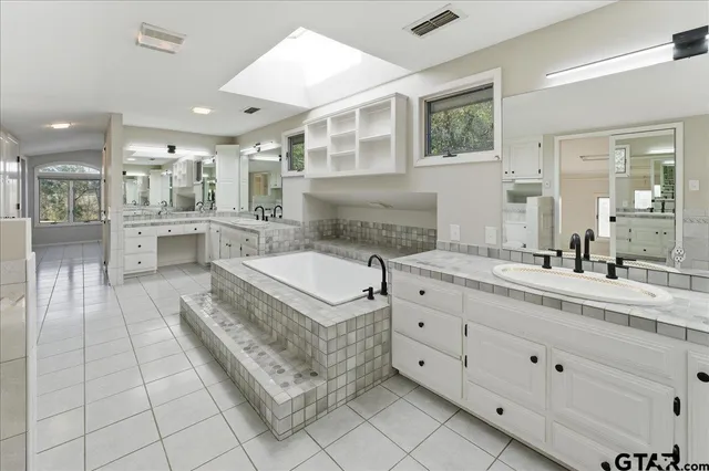 a spacious bathroom with a tub sink and mirror