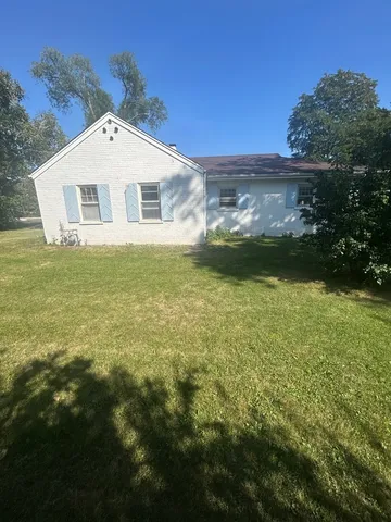 a front view of house with yard and trees in the background