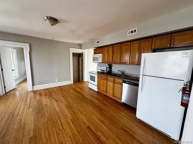 a kitchen with granite countertop wooden floors a refrigerator and a stove