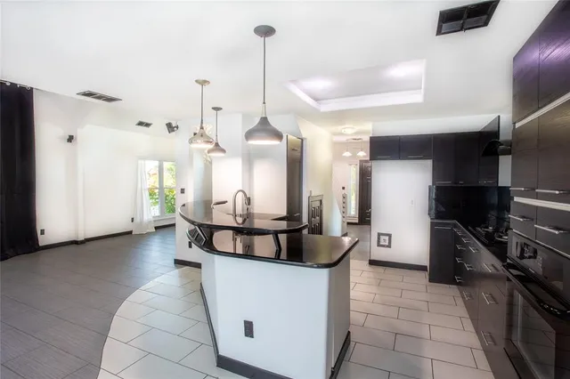 a kitchen with stainless steel appliances kitchen island granite countertop a refrigerator a stove and a sink with wooden floor