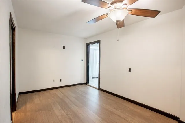an empty room with wooden floor fan and windows