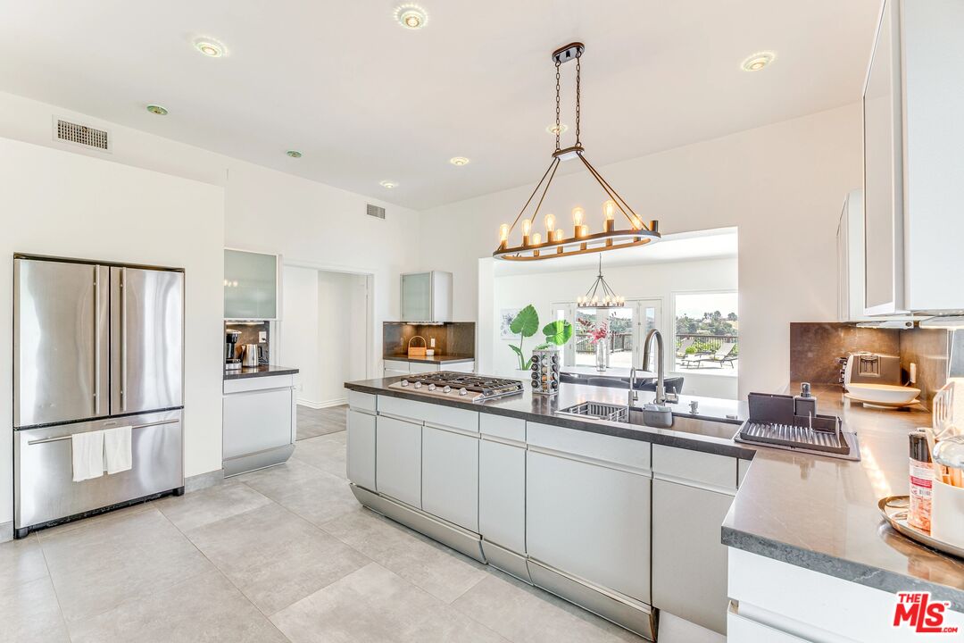 1410 Stradella Road Los Angeles, CA 90077 - Photo 11 of 42 a kitchen with stainless steel appliances a refrigerator a sink a stove a microwave a dining table and chairs