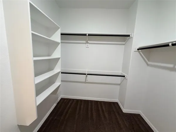 a walk in closet with wooden floor