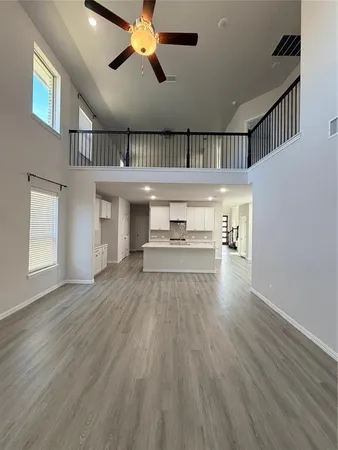 a view of a hallway with wooden floor and a ceiling fan