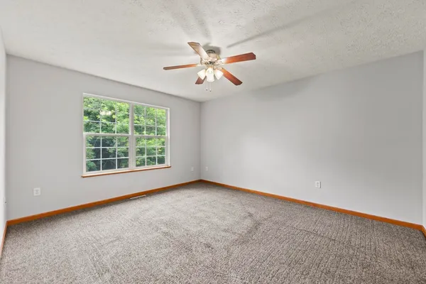 an empty room with a window and a fan