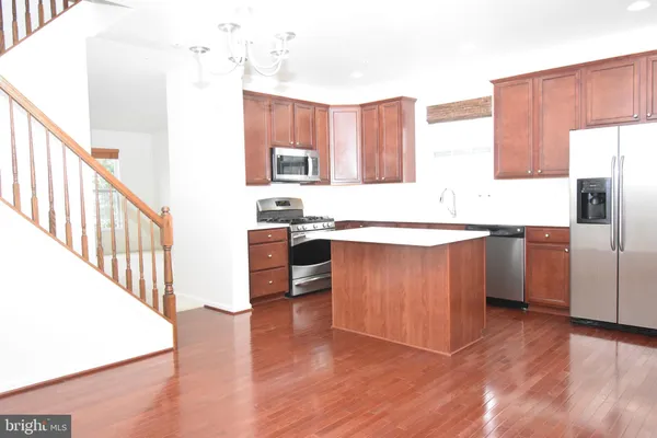 a kitchen with stainless steel appliances granite countertop a table chairs sink and cabinets