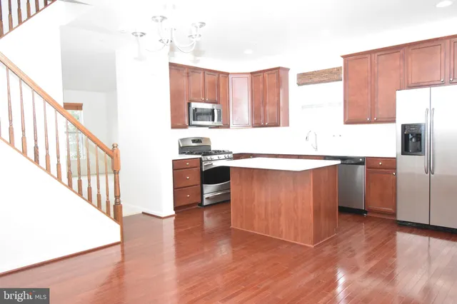 a kitchen with stainless steel appliances granite countertop a table chairs sink and cabinets