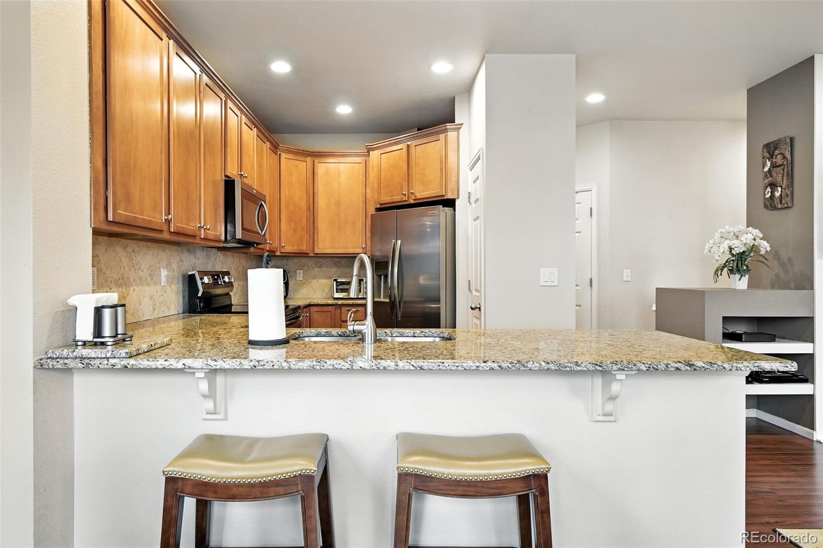 12804 Harrison Street Thornton, CO 80241 - Photo 13 of 37 a kitchen with stainless steel appliances granite countertop a stove a sink and a refrigerator