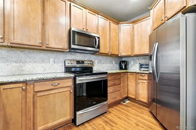 a kitchen with stainless steel appliances granite countertop a stove a microwave and a refrigerator