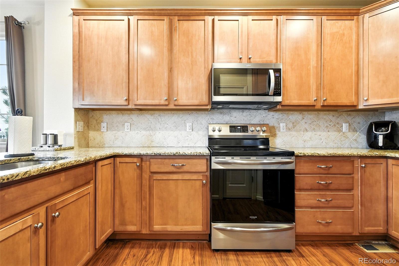 12804 Harrison Street Thornton, CO 80241 - Photo 15 of 37 a kitchen with stainless steel appliances granite countertop a stove a sink and a microwave