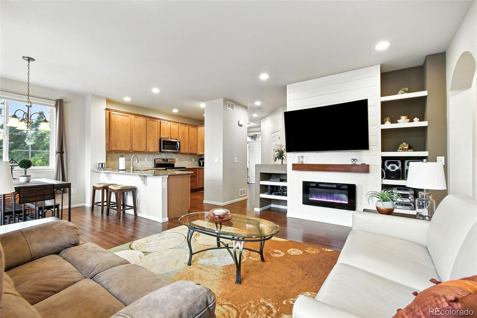 12804 Harrison Street Thornton, CO 80241 - Photo 8 of 37 a living room with furniture a fireplace and a flat screen tv