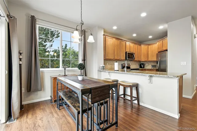 a kitchen with stainless steel appliances granite countertop a stove top oven a refrigerator a sink and white cabinets with wooden floor