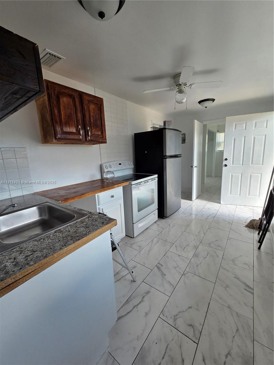 2124 South Beech Road, Unit B West Palm Beach, FL 33409 - Photo 4 of 12 a kitchen with stainless steel appliances granite countertop a sink stove and cabinets