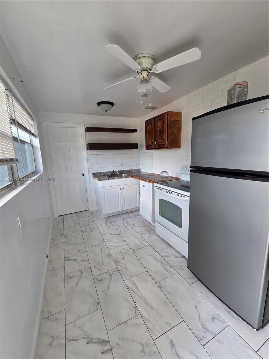2124 South Beech Road, Unit B West Palm Beach, FL 33409 - Photo 5 of 12 a kitchen with stainless steel appliances granite countertop a refrigerator a oven a sink and dishwasher