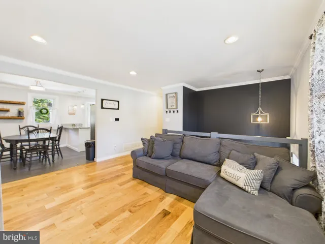 a living room with furniture and a dining table with wooden floor